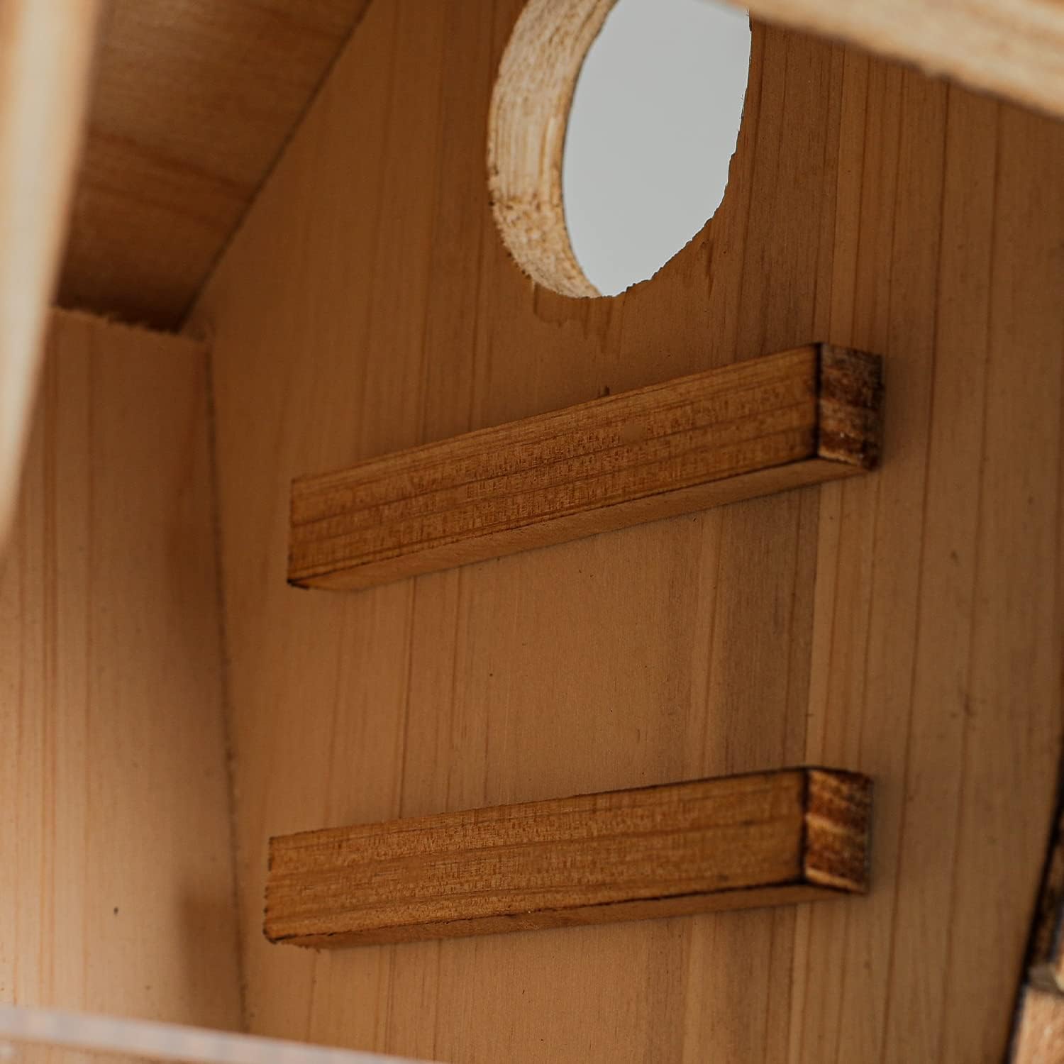 Wooden birdhouse with round entrance hole and front perch, light brown wood