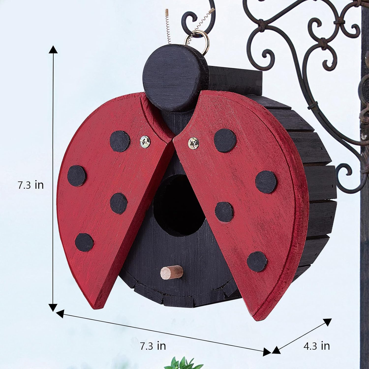 Red ladybug-shaped wooden hanging bird house with round black entrance and polka-dot wings