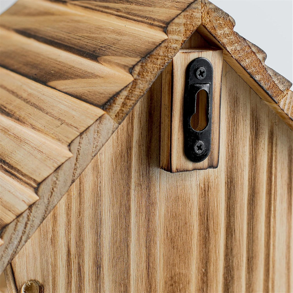 Weatherproof wooden bluebird house front with oval dark entrance and metal fastener