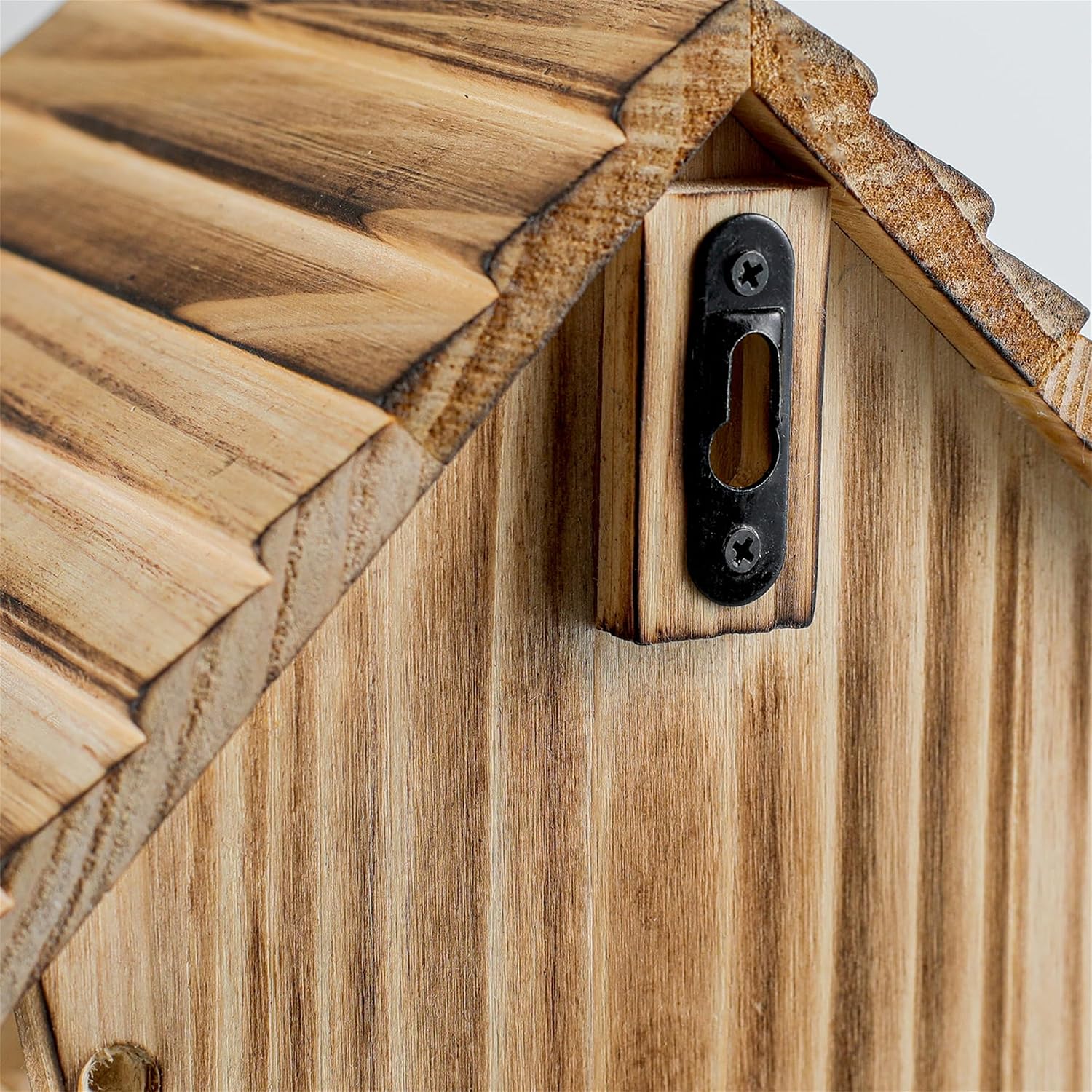 Weatherproof wooden bluebird house front with oval dark entrance and metal fastener